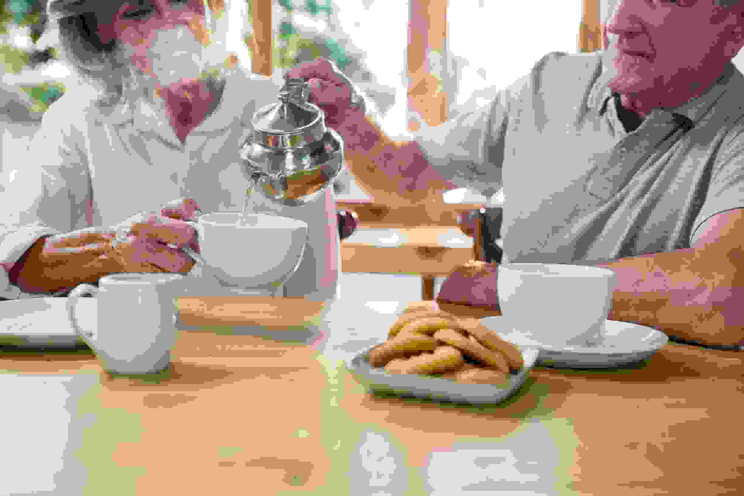 A man sitting at the table pouring tea in to a cup
